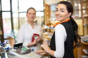 Glimlachende winkelmedewerker aan het werk in een winkel terwijl ze een klant helpt.