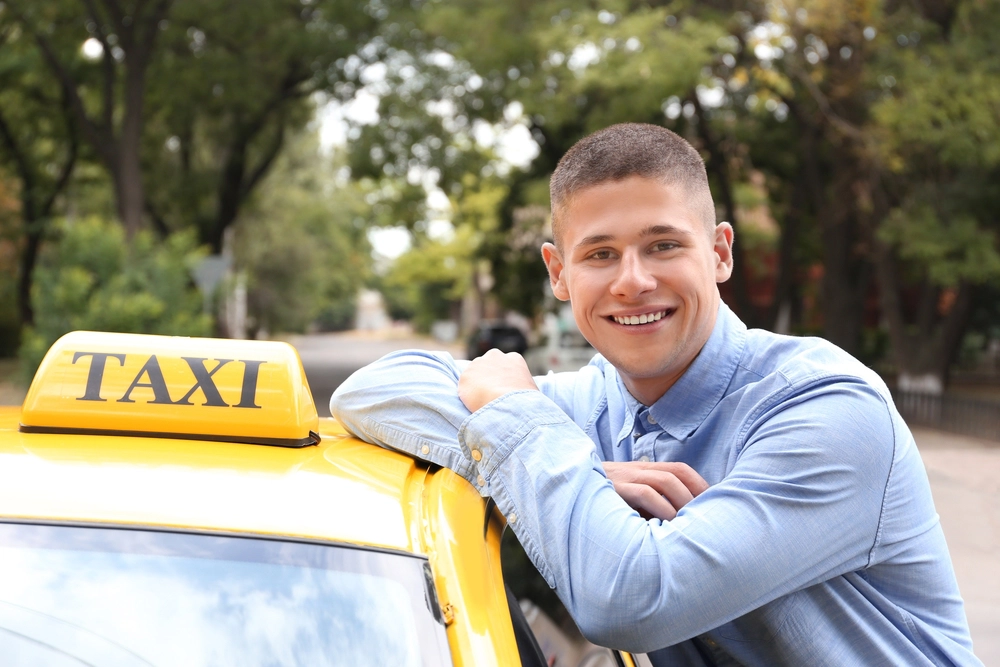 Mannelijke taxichauffeur naast zijn taxi